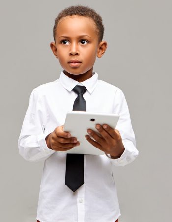 Learning, education, technology and communication concept. Handsome smart African student in school uniform posing is studio with digital touch pad tablet, using wireless internet connection